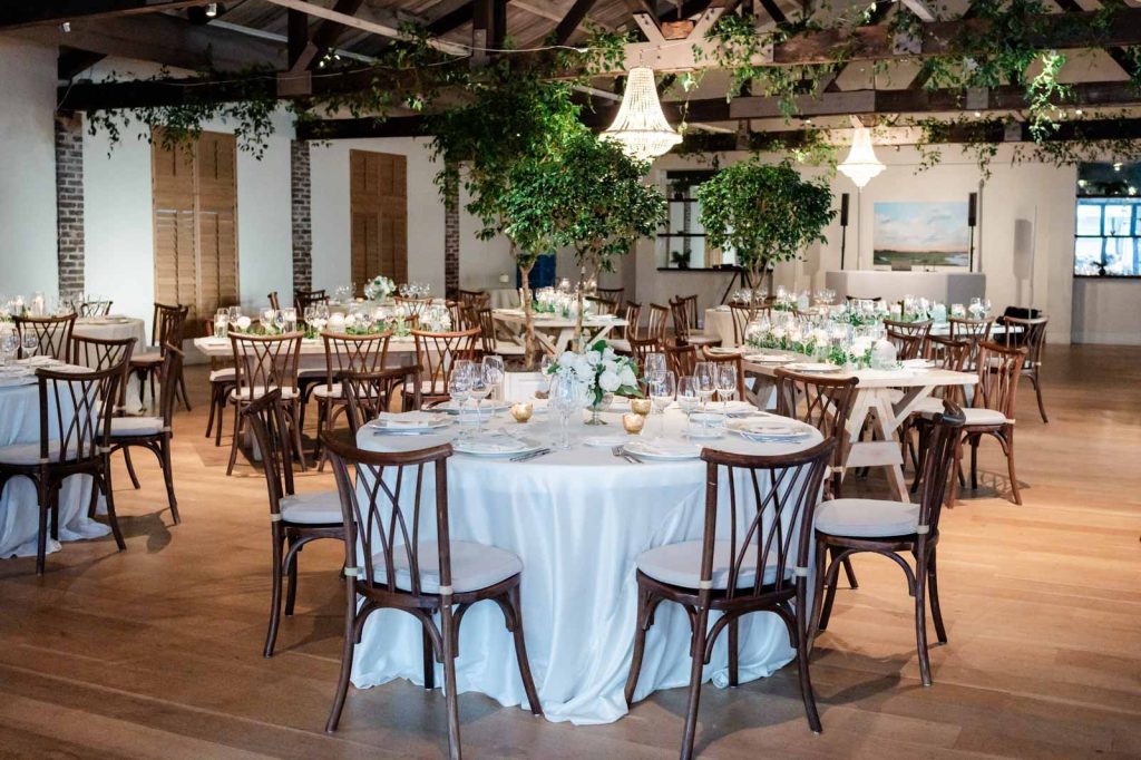Interior photo of the inside of Cannon Green wedding venue reception space with greenery and chandeliers