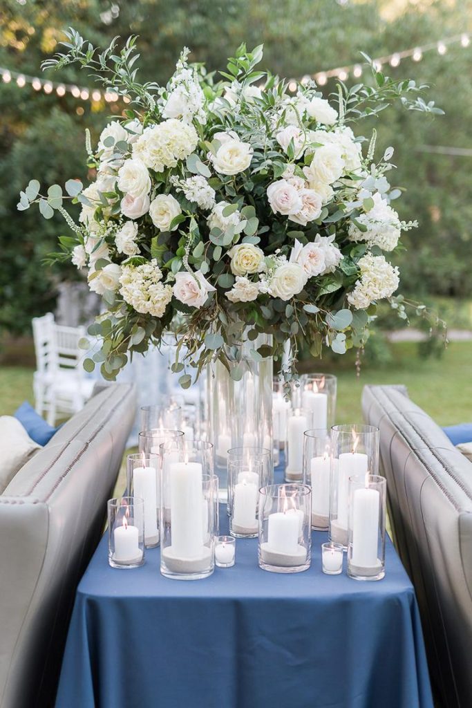 large white floral arrangement surrounded by lit candles at wedding reception