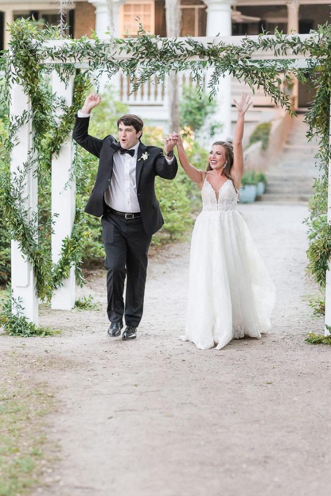 bride and groom walking into wedding reception with hands held up