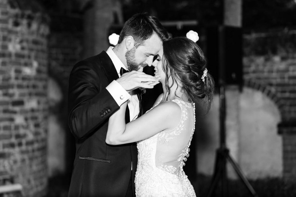 bride and groom hold hands as they slow dance at reception