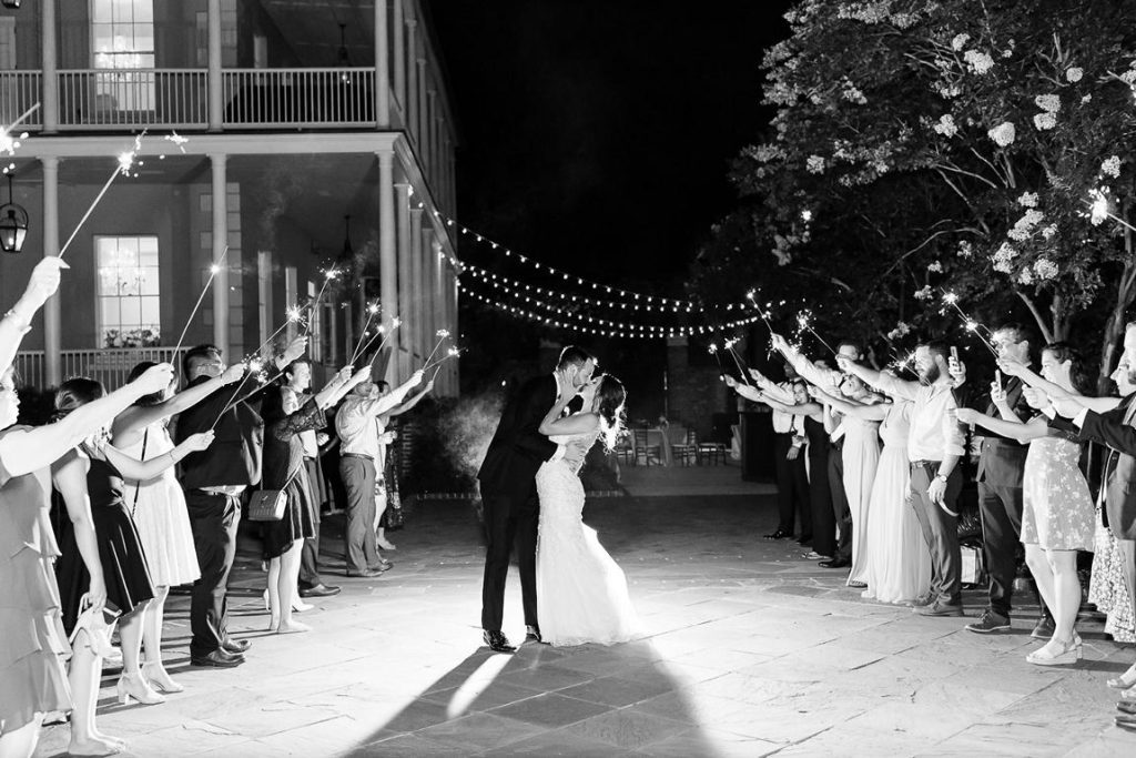 black and white of groom dipping and kissing bride during wedding sparkler exit