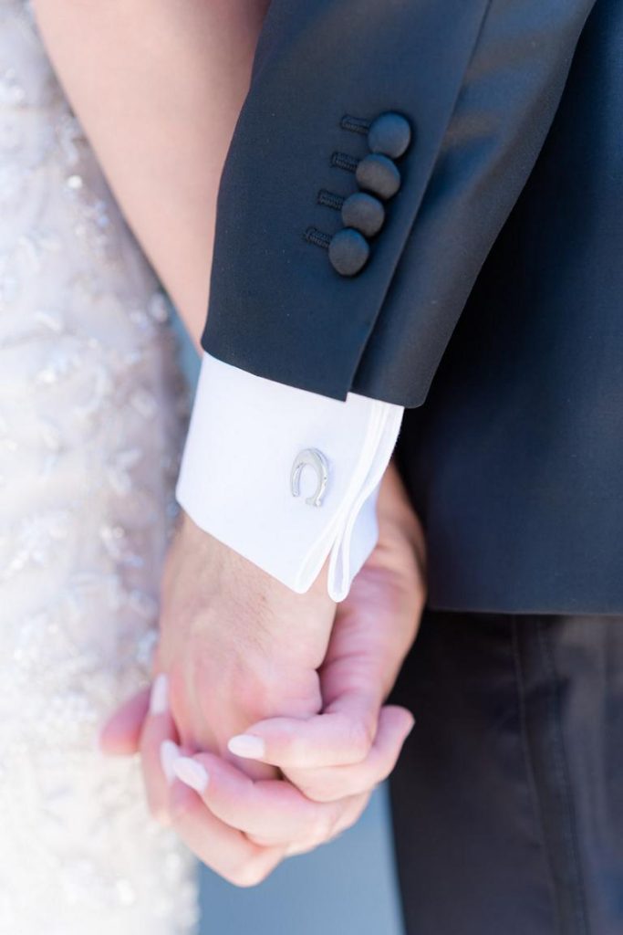 close up of groom and bride holding hands