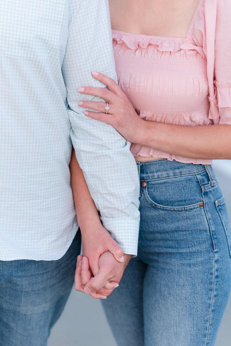 Close up of couple holding hands, engagement ring on guy's bicep