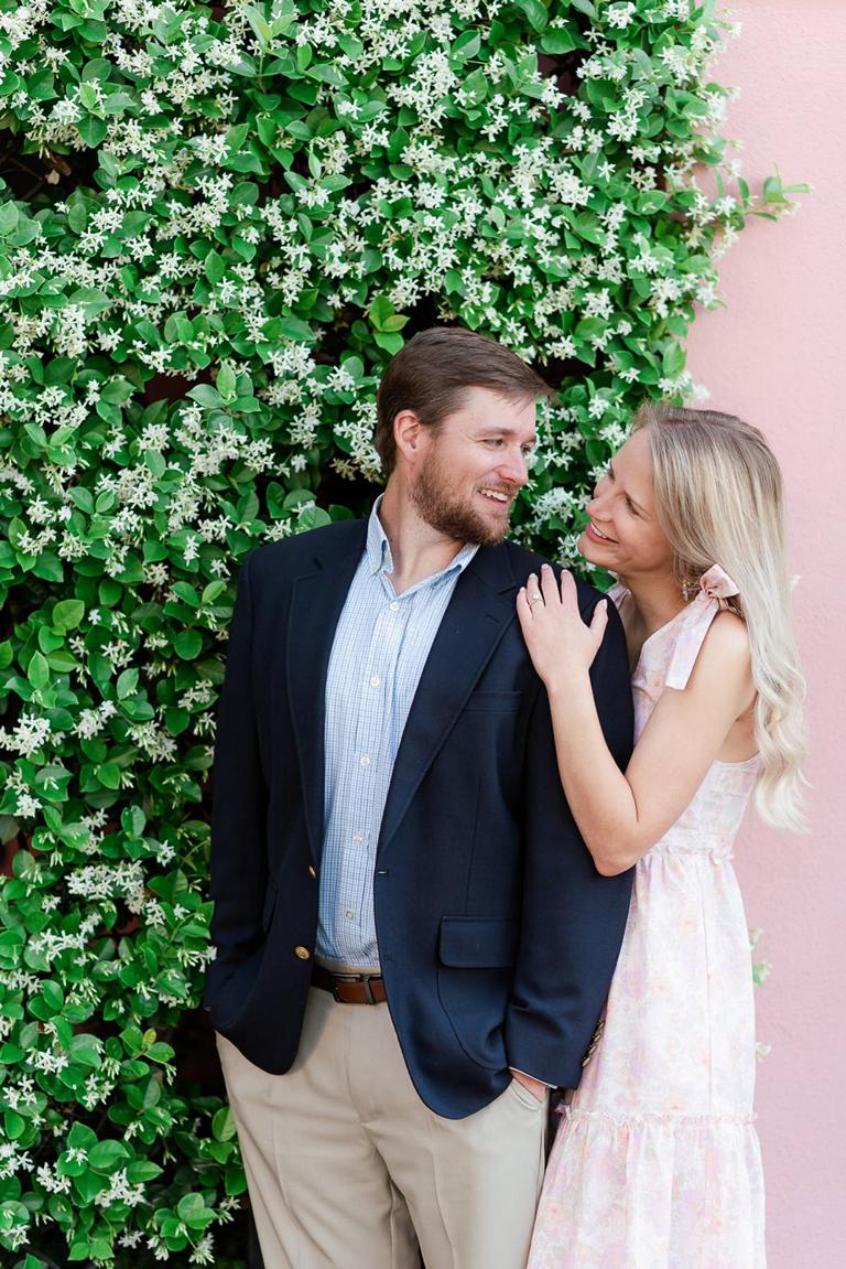 Engaged couple in front of honeysuckle blossoms looking at each other