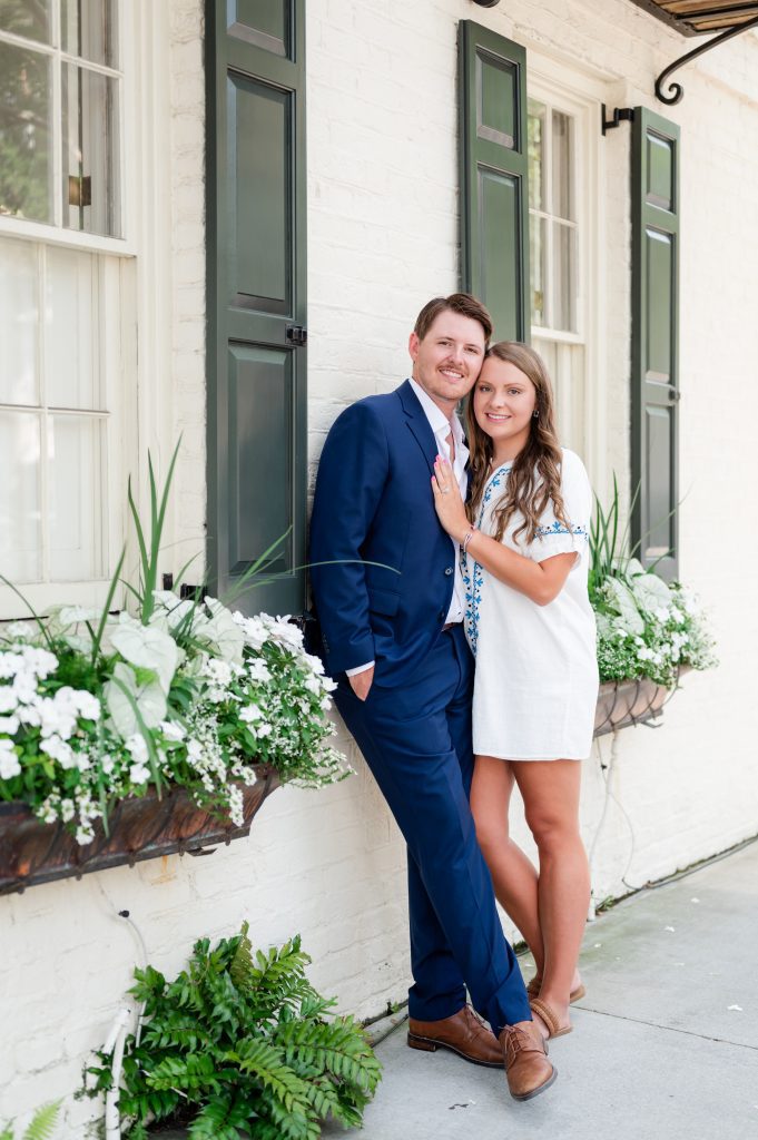 engaged couple stand between flower boxes in historic Charleston