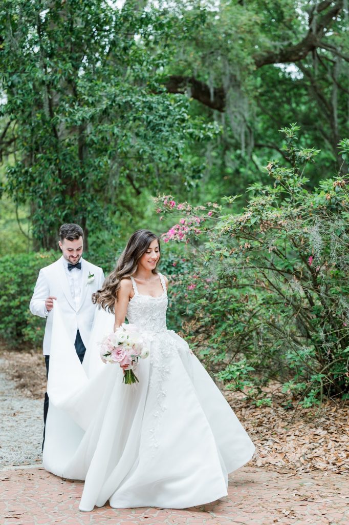 groom holds bride's dress as she walks