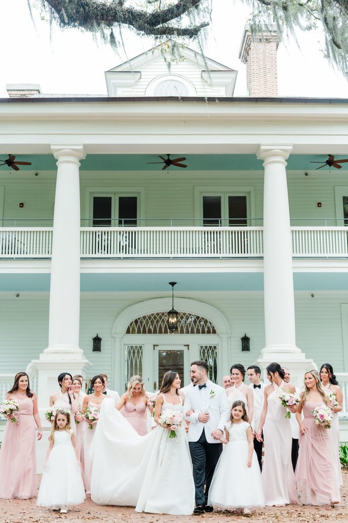 bride and groom walking with large wedding party behind them
