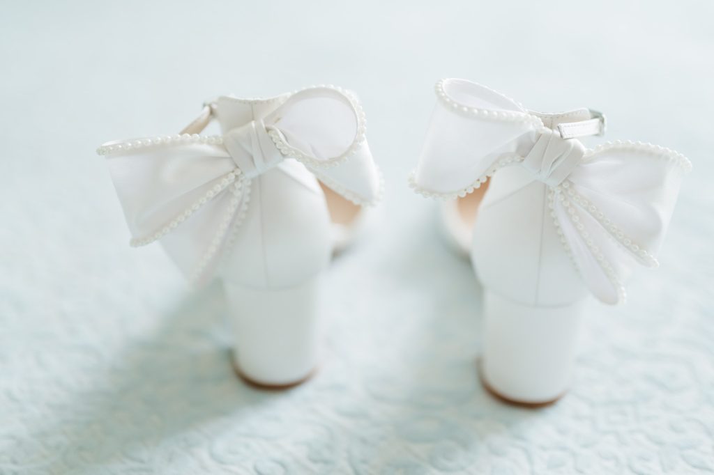 back of a pair of bride's wedding shoes with bows trimmed in pearls
