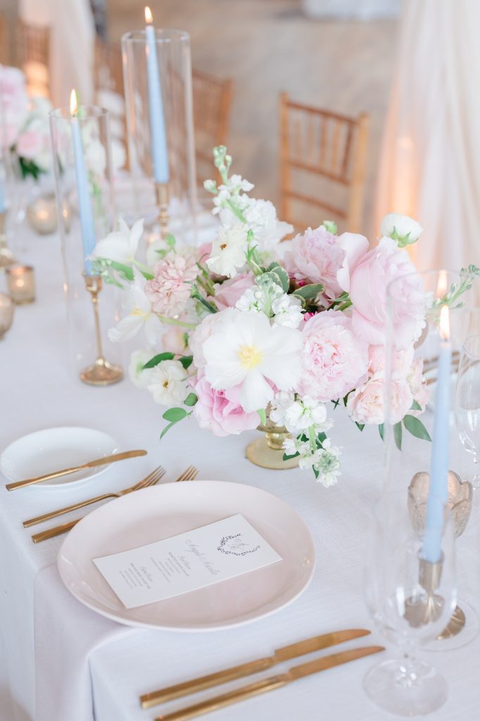 Place setting at wedding reception with pink plate and gold silverware
