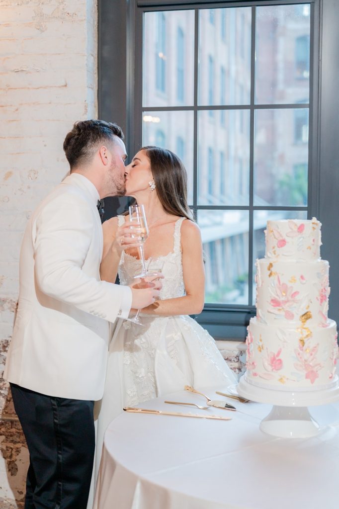 Newlywed couple kiss after cutting their wedding cake