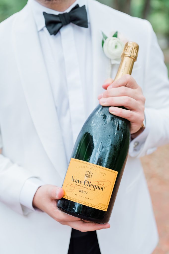 close up of groom holding magnum bottle of Veuve Clicquot Champagne bottle