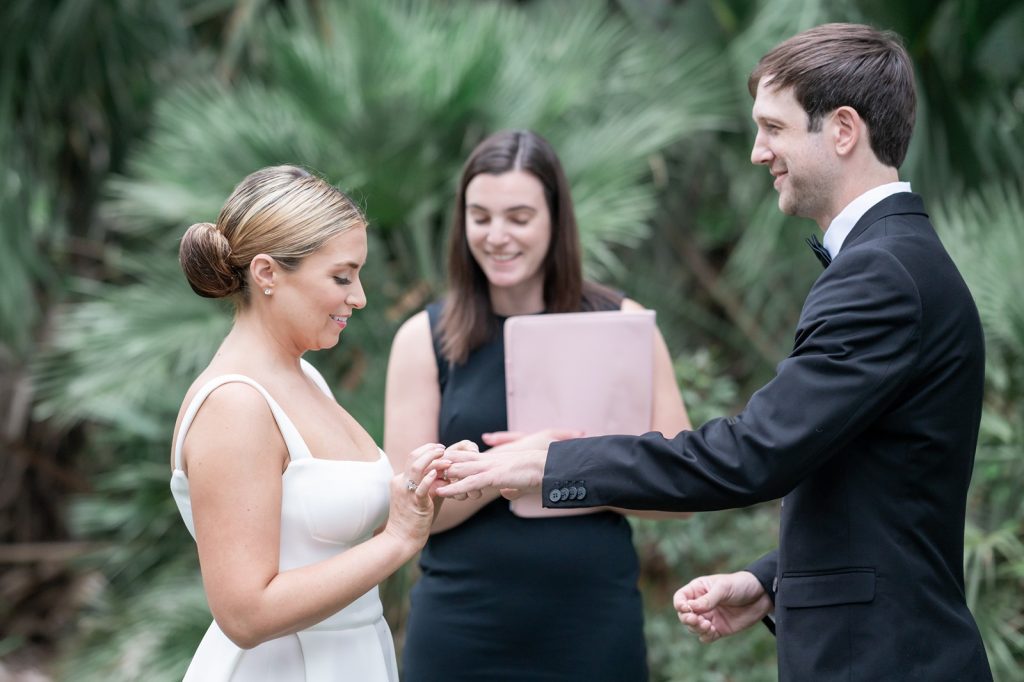 bride put wedding ring on groom's finger during wedding ceremony