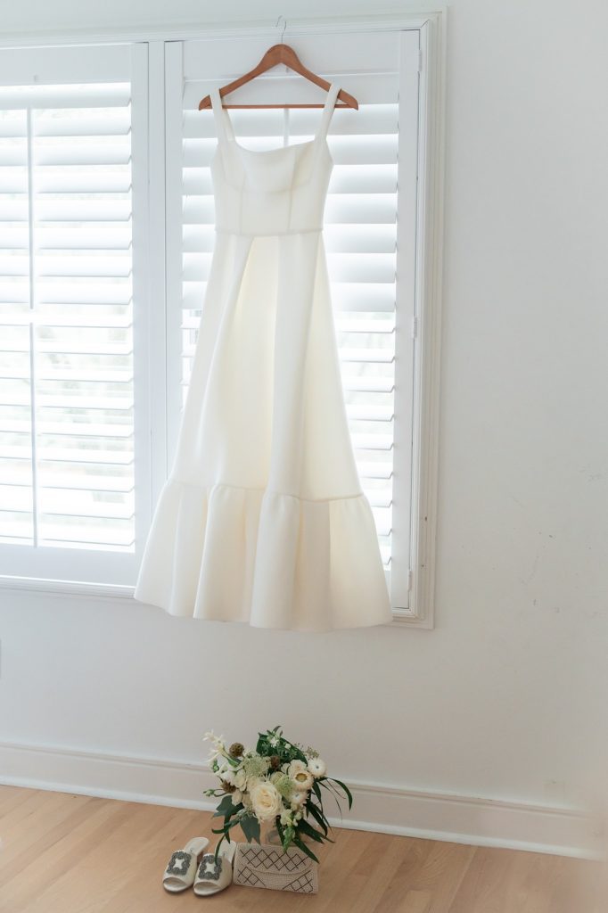 wedding dress hanging from hanger on white plantation shutters