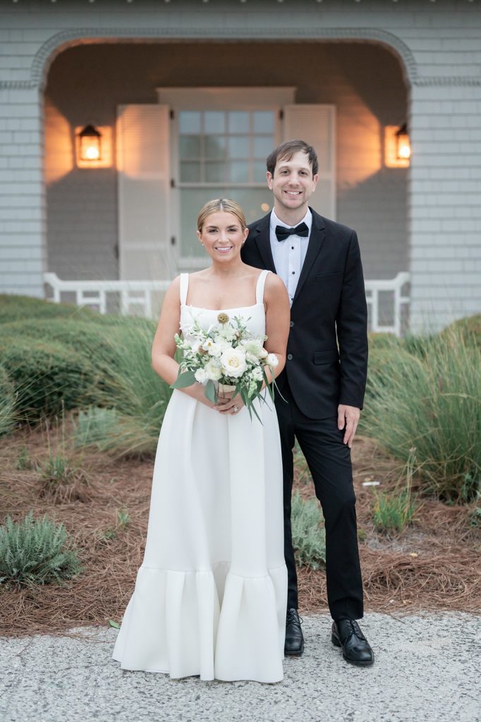 newlyweds pose in front of Ocean Course Clubhouse