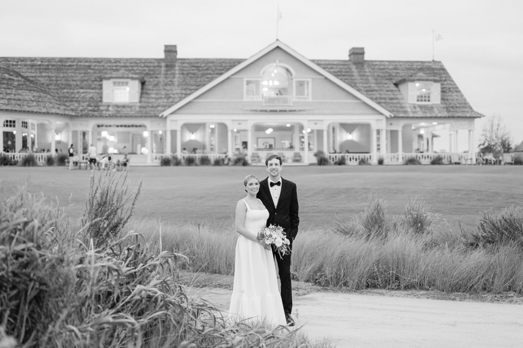 newlyweds pose in front of the backside of the Ocean course clubhouse
