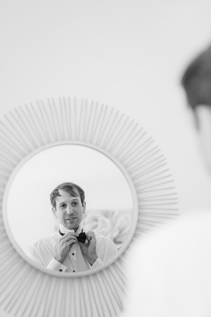 groom ties bowtie in mirror