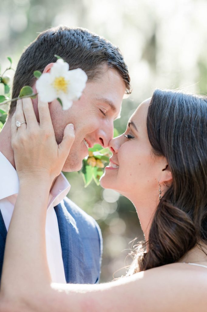 couple nuzzle nose to nose with flower bloom in foreground