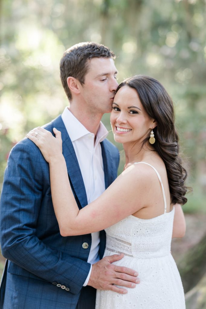 guy kisses his fiancé on the side of her forehead