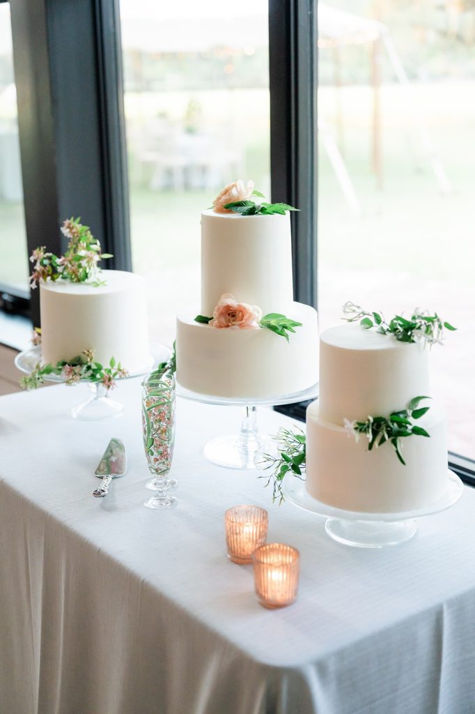three white wedding cakes with greenery on top