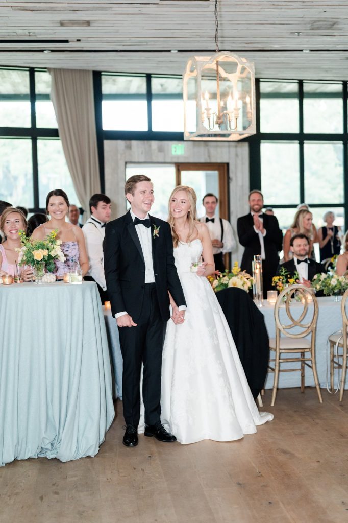 newlyweds smile while listening to a toast at their wedding reception