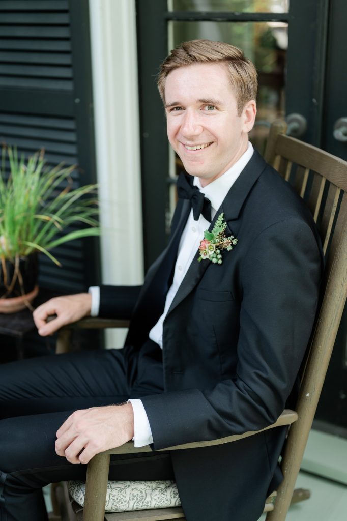 groom seated in rocking chair looking at camera