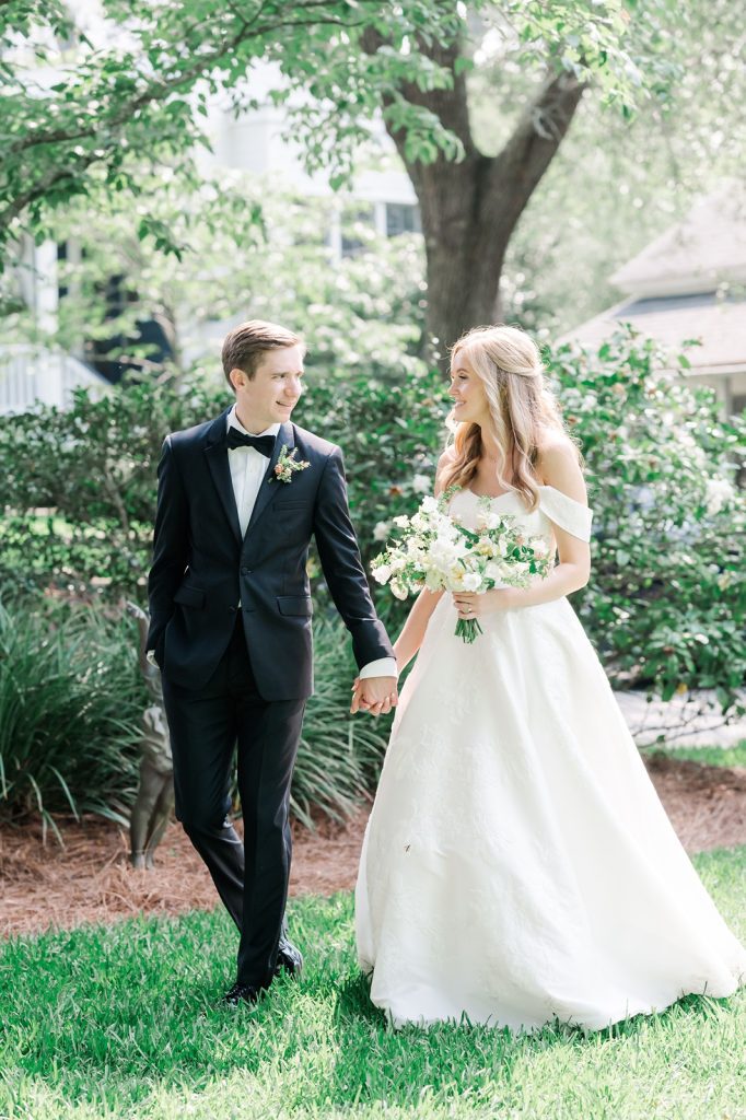 newlyweds walk holding hands looking at each other