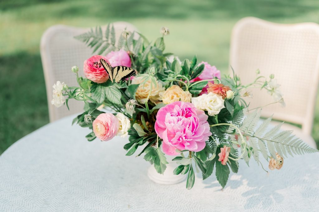 pink, yellow and green floral arrangement with live yellow butterfly landed on florals