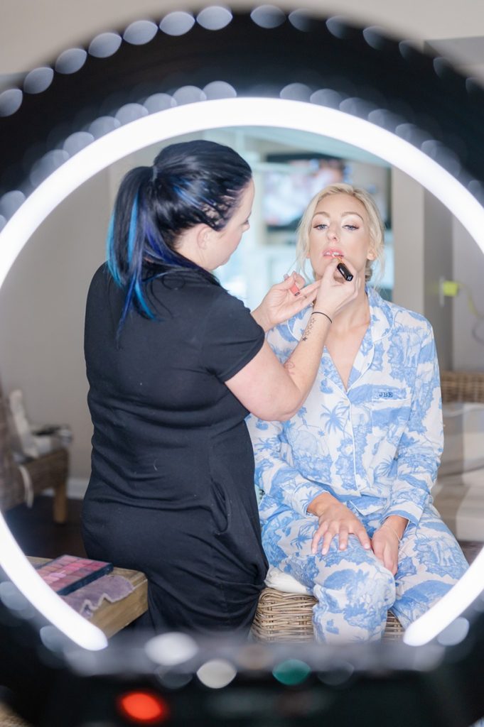 bride getting lip gloss on by makeup artist