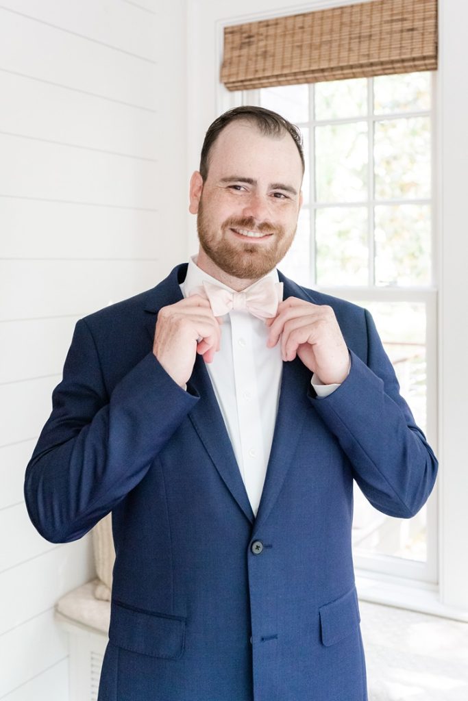 groom straightening bowtie on wedding day