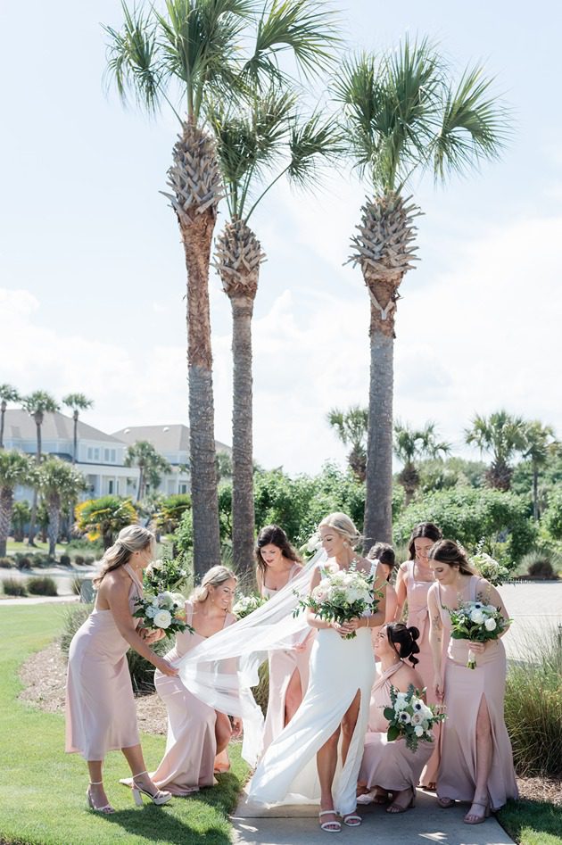 bridal party in pink dresses fluffing bride's wedding dress