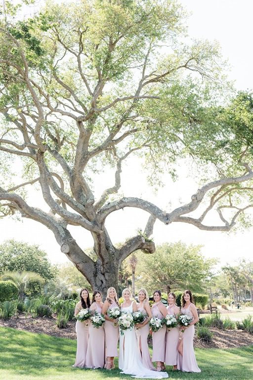 bridal party and bride standing under oak tree