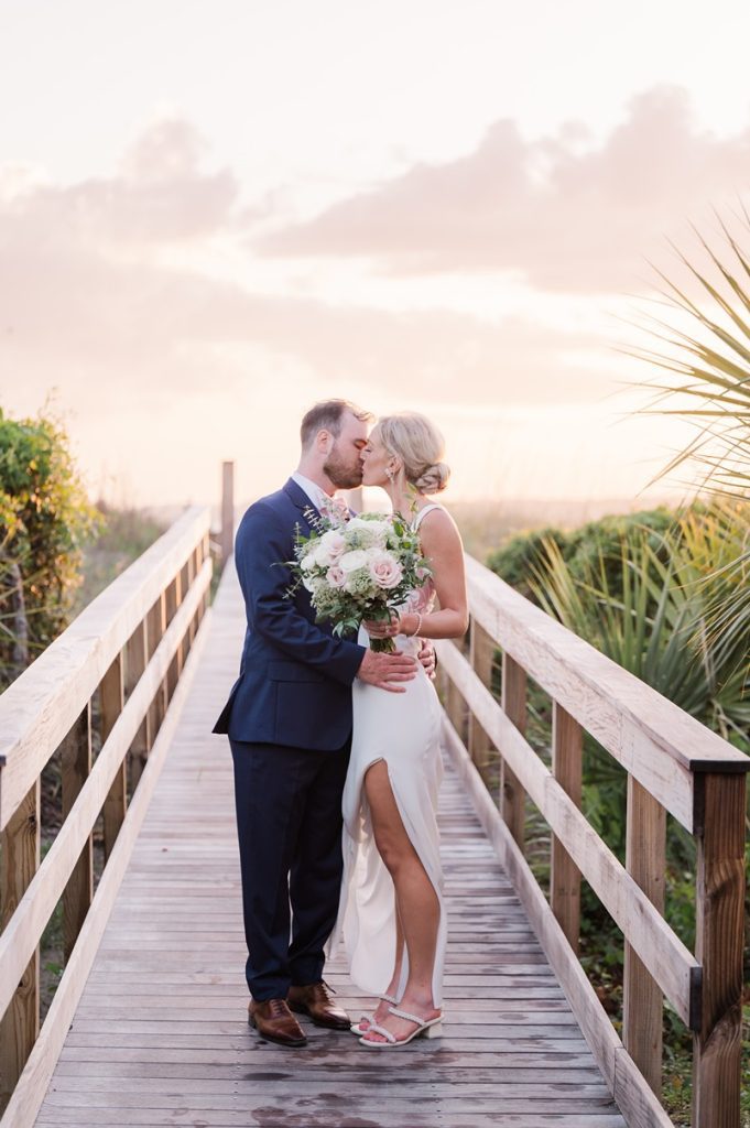 newlyweds kiss on beach boardwalk at sunset