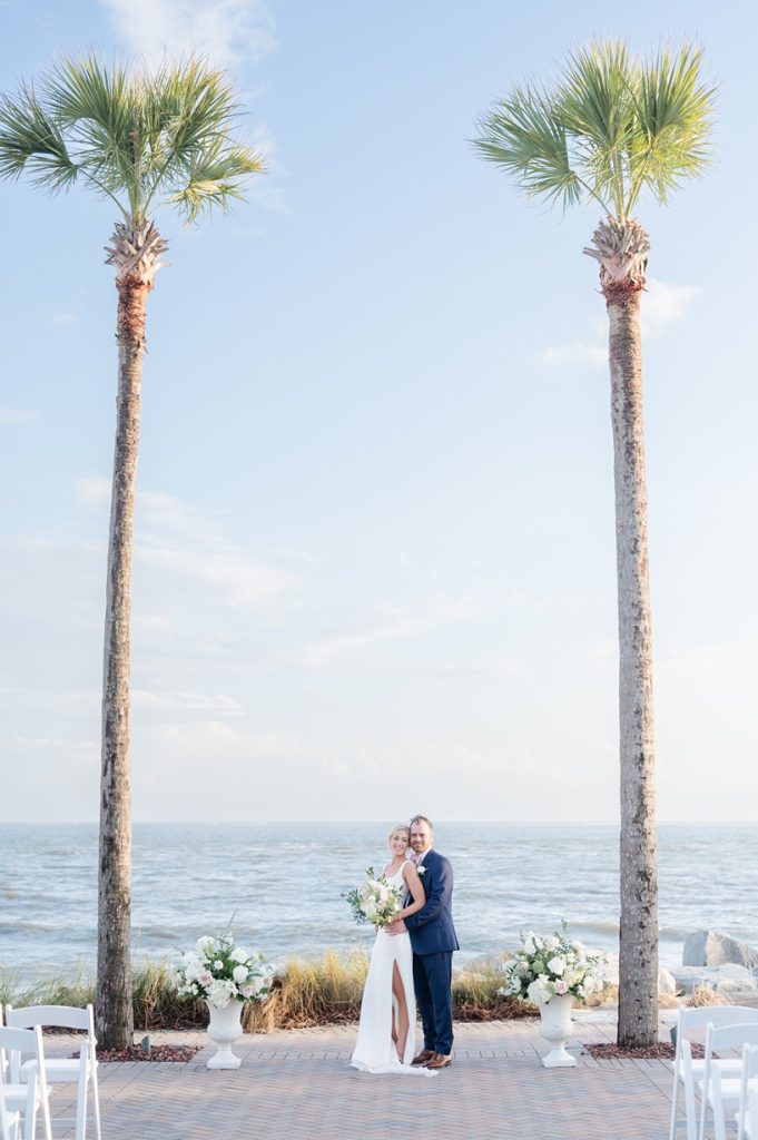 newlyweds pose in front of oceanfront ceremony site of their wedding