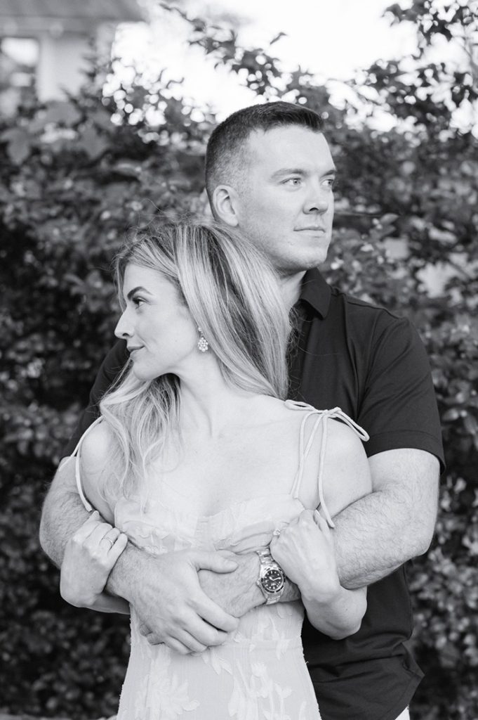 guy bear hugs girl and they both look in different directions, photo in black and white