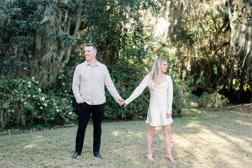 Engaged couple holds hand and look opposite way