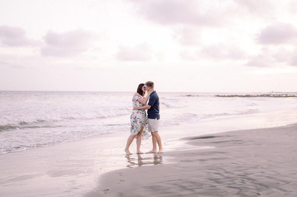 Couple kiss at beach during pink sunset