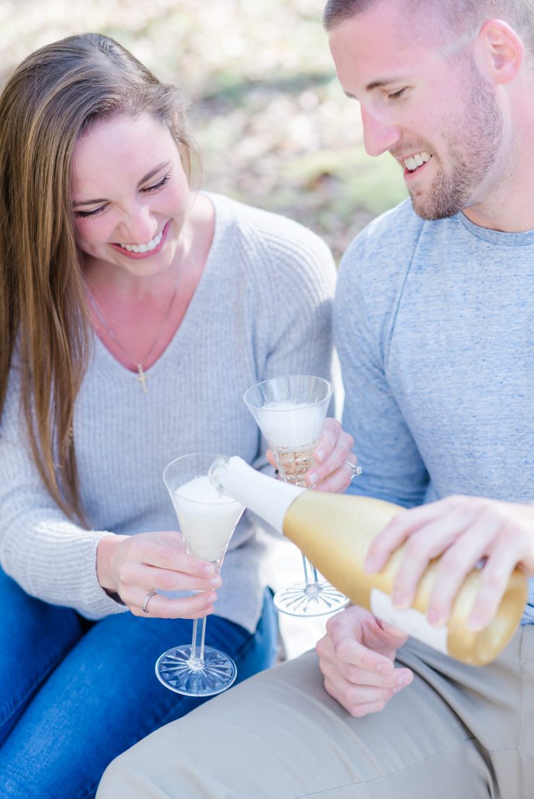 guy pours champagne into two flutes girlfriend is holding