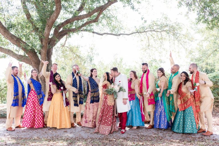 Newlyweds kiss in front of their wedding party dressed in formal Indian Wedding attire