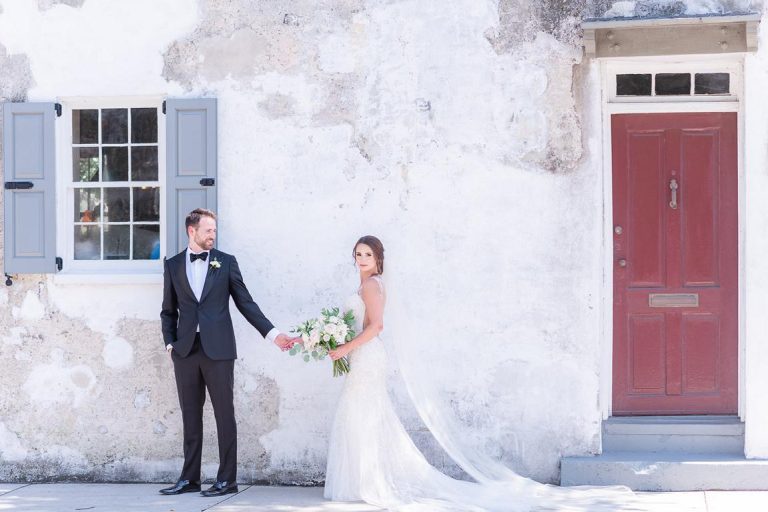 groom leads bride down sidewalk in front of Zero George Hotel