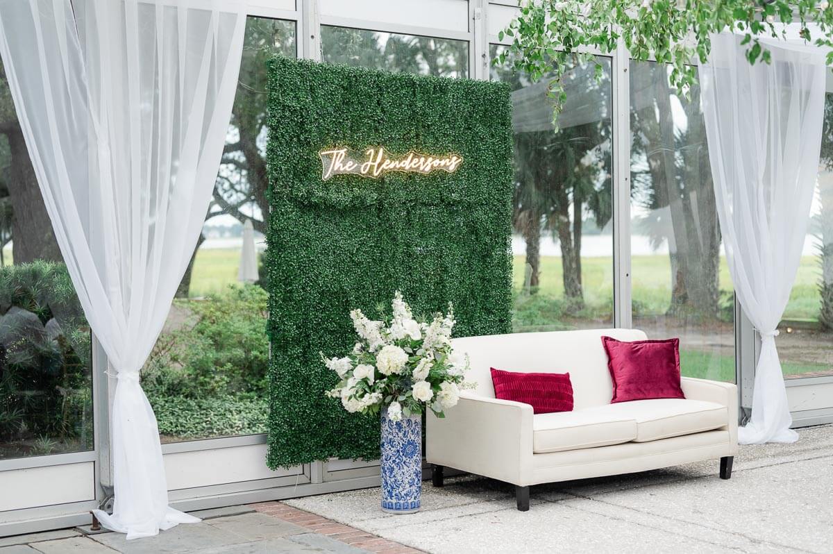 white couch with greeny wall behind it with neon saying"The Hendersons"