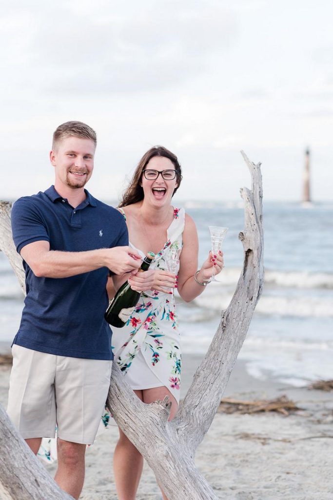newly engaged couple pop champagne to celebrate on Folly beach