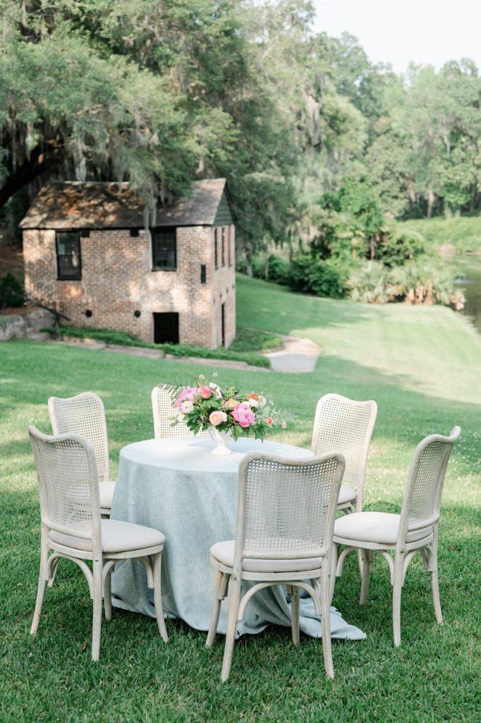 Wedding cocktail set up of table with blue lines and white wicker back chairs