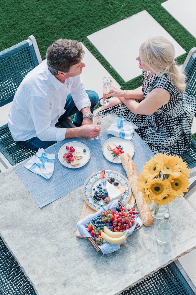 Couple toasts anniversary with champagne while picnicking