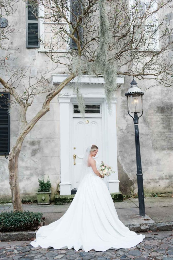 bride looking at bouquet while standing in front of white doorway on Chalmers Street