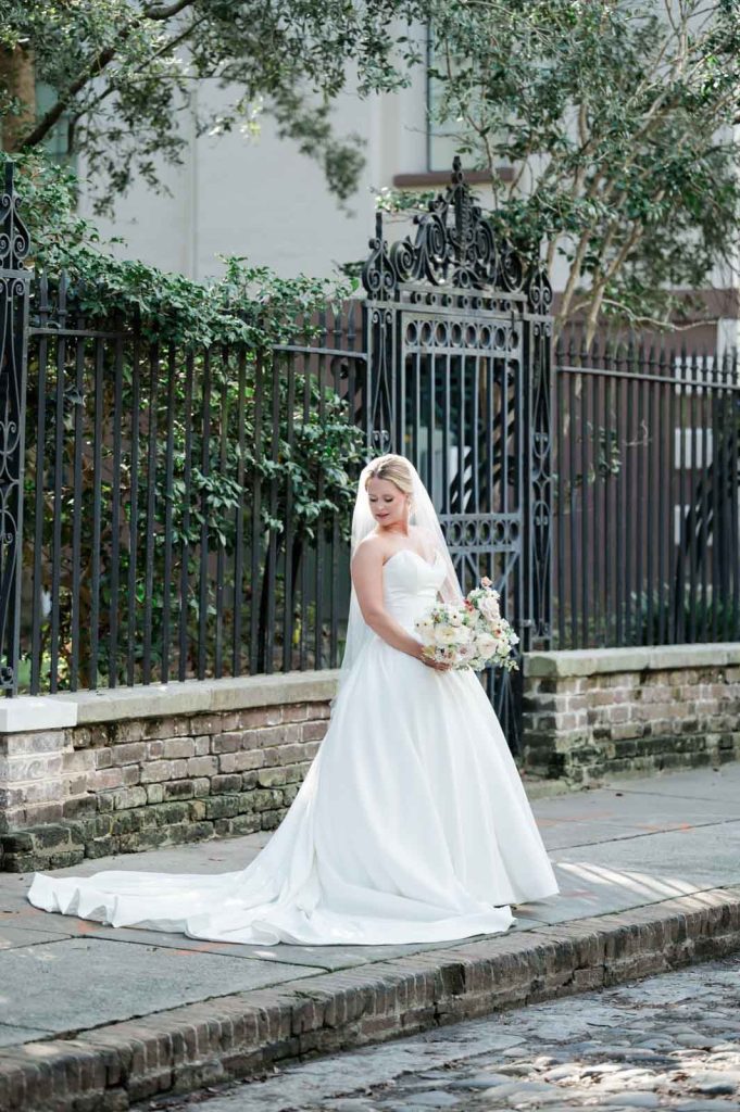 bride looking down shoulder in front of black iron fence